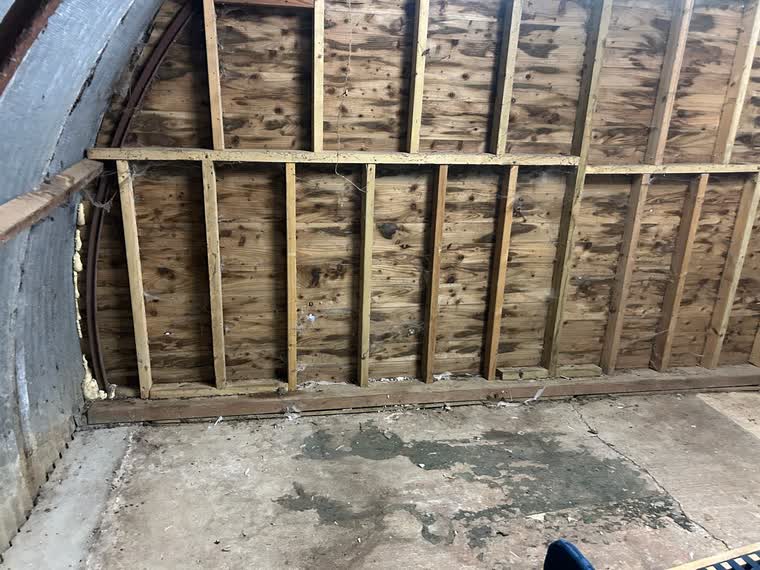 The same shed emptied to bare timber framing with the floor swept clean