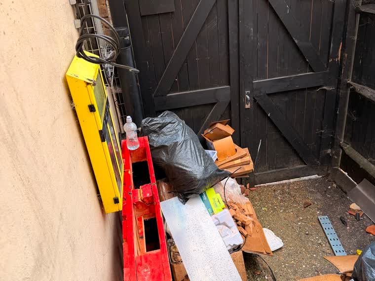 Side yard blocked with bags, broken boards and loose material before clearance